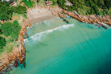 Beach, stones and transparent ocean in Brazil. Aerial view of tropical beach in Florianopolis