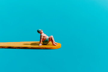 miniature man sitting on a yellow diving board