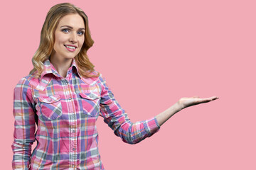 Pretty woman showing copy space on her palm on pink color background. Young woman presenting something with open hand palm.