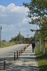 Rear view of a male walking on the sidewalk in rural area