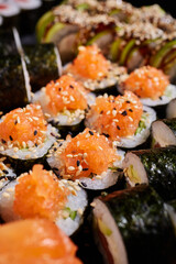 Close up of homemade sushi with raw salmon, cucumber, avocado and sprinkled with sesame seeds.