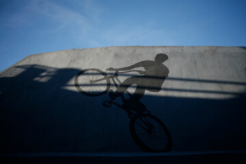 Black silhouette of a cyclist rider who is depicted with paints on the wall bridge