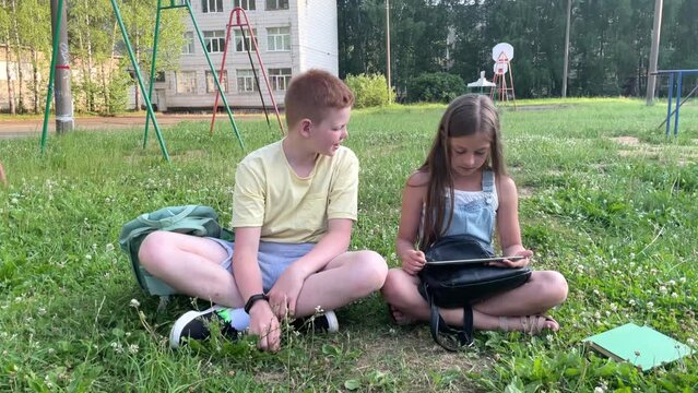 a boy and a girl on the school playground after lessons study lessons with a tablet and do homework, it's time for school, a new school year