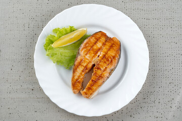 Salmon teriyaki steak with lemon and lettuce.