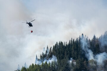 Aerial firefighting Helicopter transporting water to burning forest