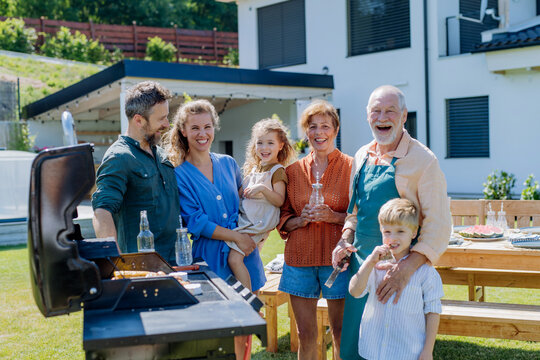 Multi Generation Family Grilling Outside On Backyard In Summer During Garden Party