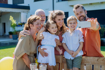 Multi generation family taking selfie on backyard in summer during garden party