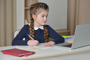 Online education. Cute little girl studying at home with laptop.

Adorable kid in school uniform...