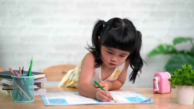 Cute little child painting with colorful paints. Asian girl using wood color drawing color.Baby artist activity lifestyle concept.