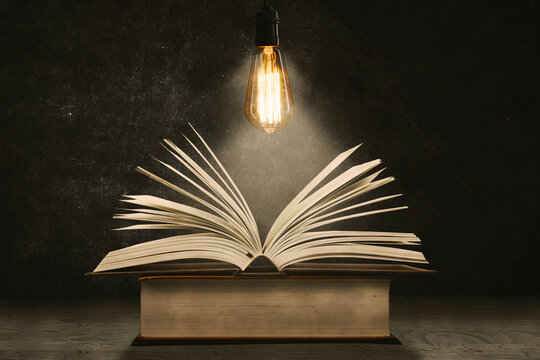 Close up of open book under a bright bulb on table