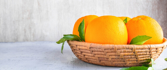 Fresh orange fruit  in the basket and orange leaves on the white wooden background