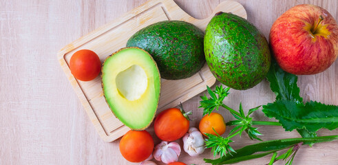 Top view of fresh avocado fruit halved and composition and ingredients for cooking