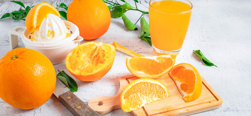Homemade squeezed orange juice and fresh oranges fruits on a white wooden background. Cut the...