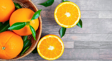Top view of fresh orange fruit in baskets and halved orange fruit on the wooden background.