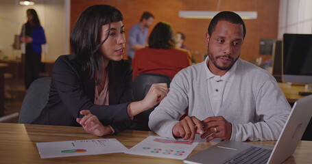 Fototapeta premium Diverse colleagues discussing work. A black employee explaining new job for a latin hispanic female staff