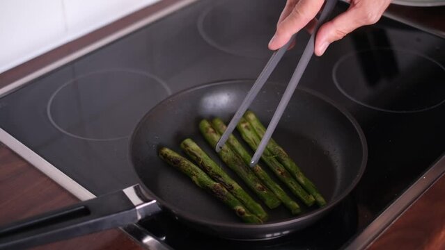 man fry asparagus on a teflon pan. proper nutrition vegetarianism