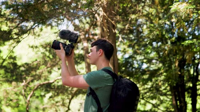 Digital content creator with professional mirrorless camera and microphone shooting videos in a forest setting