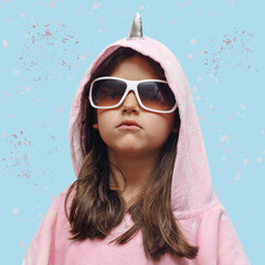 little girl in a pink poncho and sunglasses very serious, funny child in a unicorn costume isolated...