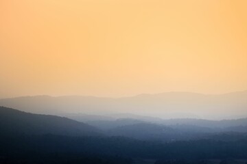 Foggy mountains over a background of an orange sky