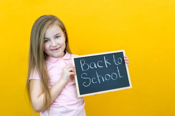 schoolgirl holding a tablet in her hands with the inscription Back to school on a yellow background.