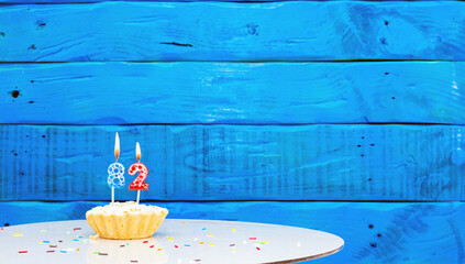 Festive background with a cake on the background of blue boards, copy space, a beautiful background for a birthday with a number a candle with a figure 82