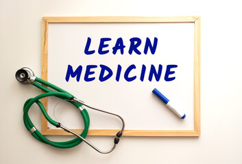 The text LEARN MEDICINE is written on a white office board. Nearby is a stethoscope.