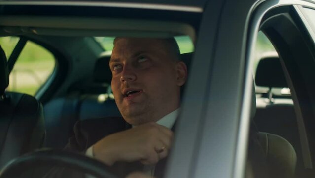 Man in a business suit sits in car and rolls his eyes standing in traffic.Feel angry stress depression. Look serious automobile. Frustrated tired. Close up.Slow motion.