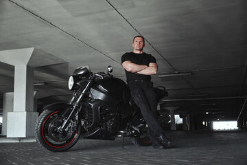 A man and motorcycle in underground parking garage