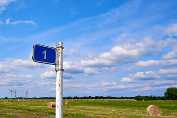 Distance road sign. Sign 1 kilometer against the blue sky and summer field