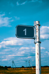 One kilometer road sign against a blue sky with white clouds