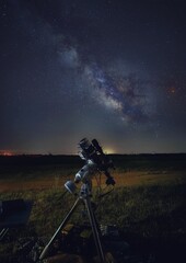 Vertical shot of a telescope in starry night background at night