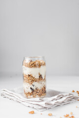 Granola and yogurt parfait in a can shaped glass, oats and nuts parfait, toasted honey granola with layers of yogurt in can glass cup 