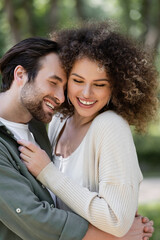 joyful young man smiling and hugging happy and curly woman.