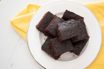 Pieces of chocolate cake on a white plate with yellow napkins