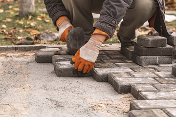 Laying paving slabs close-up. Road surface, construction. Sidewalk repair. Worker laying stone paving slab. Laying tiles in the city park garden . Manual fixed tessellated paving slabs