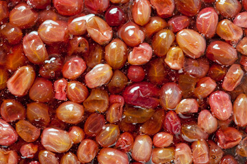 Close-up shot of red ripe gooseberry jam in sweet syrup.