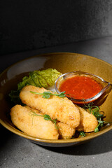Cheese sticks in minimal style on gray stone background. Fried Cheese with spicy sauce on concrete table with hard shadow. Mozzarella sticks on dark  stone background. Minimal menu concept.