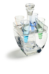 Kit with liquor bottle, four green and blue shot glasses, on a glass container, isolated on white