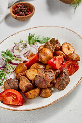 Traditional georgian dish odjahuri with meat and potatoes. Roasted pork fillet and potatoes with onion and tomatoes. Stew meat and potatoes. Eastern food with pork and spices