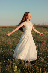Fototapeta premium Romantic woman dancing in a wonderful flower field. Warm sunset colors