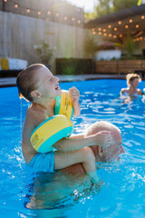 Grandfather with his granson having fun together when playing in the swimming pool at backyard.