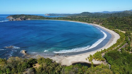 Aerial view of the blue sea and green shoreline with sandy beach.