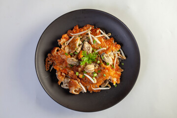 Hot pan of crispy fried oyster omelette served with bean sprout and spicy sauce.