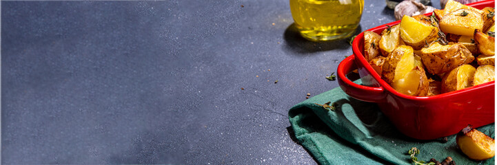 Slices of fried or baked potato wedges with herbs and spices in frying pan copy space
