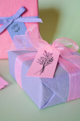 purple gift box with pink ribbon and bow and with tag