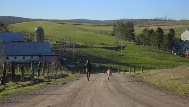 Woman walking on a dirt road with her daughter.