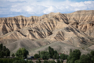 Scenic shot of desert badlands in Kyrgyzstan with farm in the foreground