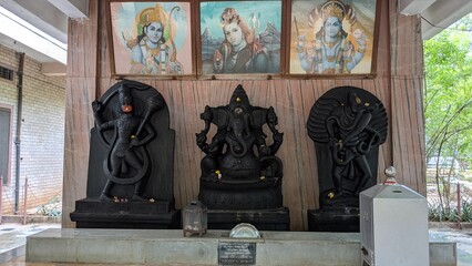 Closeup of Hanuman, Ganesha, Garuda stone statues with Rama, Shiva & Vishnu images in the backdrop