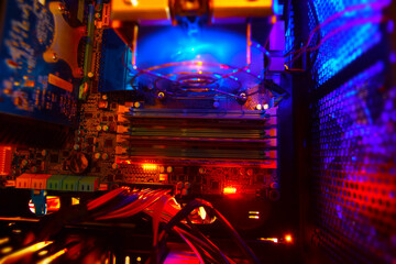 Inside a high performance computer. Computer circuit board and CPU cooling fans illuminated by...