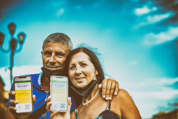 Happy couple visiting city with covid green pass. Man and woman ready to go on a trip with screenshots of the vaccination.